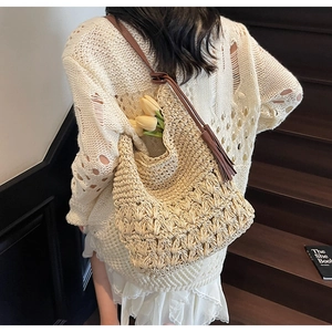 Détail du sac cabas en paille tressée avec bandoulière marron et pompon décoratif