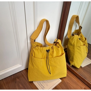 Detail of yellow drawstring bucket bag with outer pockets and adjustable wide strap