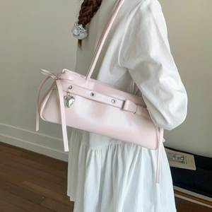 Detail of light pink shoulder bag with bow decor and silver heart pendant for women