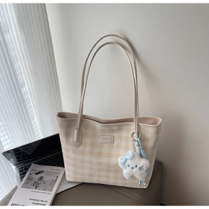Detail of beige plaid tote bag showing leather logo and cute white plush cloud charm