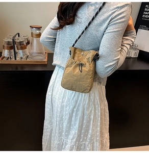 Close-up of khaki nylon crossbody bag featuring drawstring pocket and woven strap detail