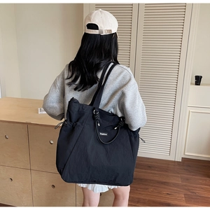 Détail du sac cabas en nylon noir avec sangle à nœuds, cordon latéral et logo Fashion