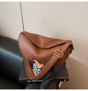 Dettaglio della pelle martellata marrone scuro su una borsa a mezzaluna vintage con fibbia