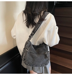 Close-up of vintage washed denim crossbody bag featuring multiple front zipper pockets