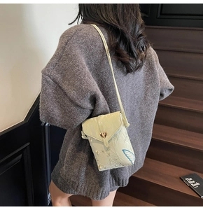 Détail du sac de téléphone vert brodé avec fermoir coeur et motif floral sur modèle