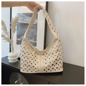 Detail of punk style bucket bag featuring silver hollow rivets and studs on beige leather