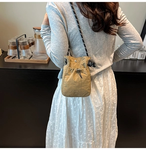Close-up of khaki drawstring bucket bag with textured fabric and woven rope strap