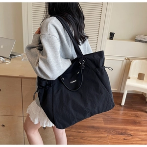 Détail macro du grand sac cabas en nylon noir avec cordon de serrage et étiquette mode