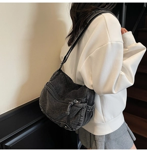 Detail view of large charcoal denim crossbody bag with vintage washed texture and pockets