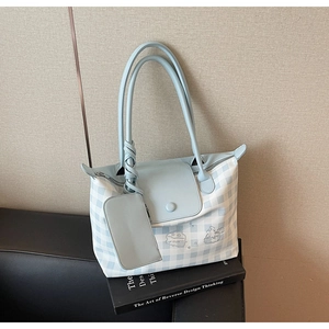Detail of blue and white checkered tote bag featuring a leather flap and mini pouch attachment