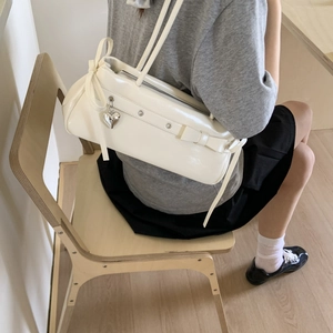 Close-up of white patent leather shoulder bag with bow and silver heart pendant
