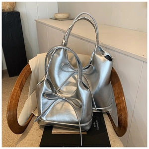 Detail view of large and small metallic silver tote bags with stylish bow tie decoration