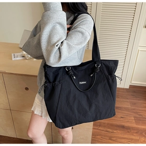 Détail du grand sac cabas noir en nylon avec poignées en corde et poches latérales