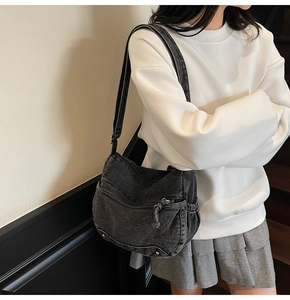 Detail view of large grey denim hobo bag with multiple zippers and adjustable strap