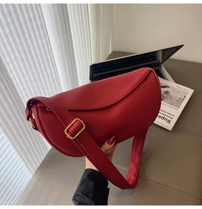 Dettaglio borsa a mezzaluna in pelle rossa martellata con fibbia in metallo dorato