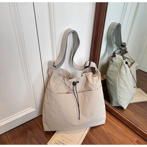 Detail of beige nylon shoulder bag with drawstring closure and large front pocket