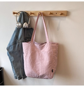 Detail of pink tote bag made of pleated nylon fabric with shoulder straps in a cozy setting