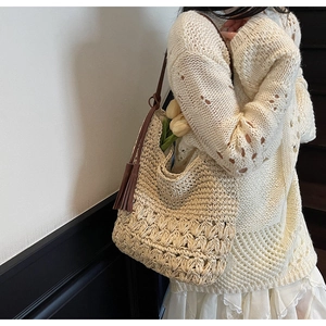 Détail d'un sac cabas en paille tressée avec pompon en cuir marron et texture