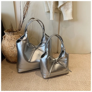 Detail of silver bow hobo bag set showing soft metallic PU texture in a cozy home setting