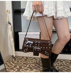 Detail view of dark brown patent leather shoulder bag with silver studs and buckle