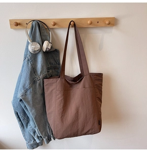 Detail of coffee brown nylon tote bag with front pocket and textured finish