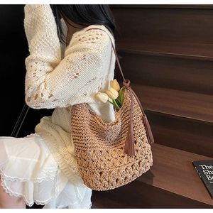 Détail du sac cabas en paille tressée marron avec glands en cuir et fines bretelles