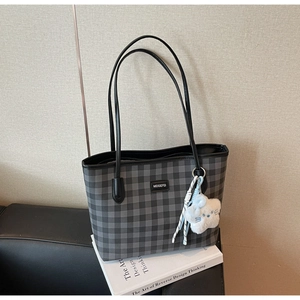 Detailed view of the checkered tote bag texture with a star charm and black strap