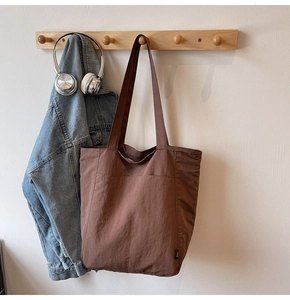 Detailed view of the dark brown nylon tote bag with front pocket and retro texture