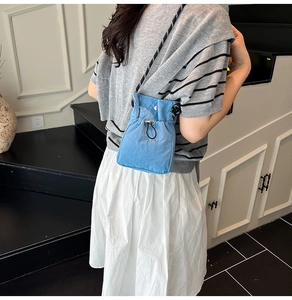 Detail of blue drawstring crossbody bucket bag with woven rope strap and metal snap