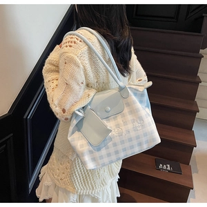 Detail view of large blue checkered tote bag with matching coin pouch on a model