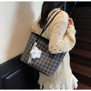 Detail of grey checkered tote bag with MEIGEFEI logo and a cute white plush cat charm