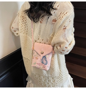 Détail de la pochette bandoulière rose brodée avec motifs floraux et fermoir coeur doré