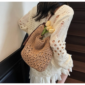Détail du sac seau en paille tissée avec bandoulière en cuir marron et maille ajourée