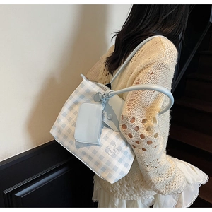 Detail view of light blue checkered tote bag with cartoon character embroidery on straps