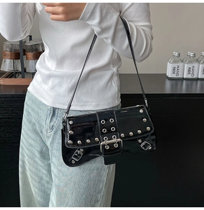 Detalle del bolso de charol negro bajo el brazo con ojales plateados y hebilla punk