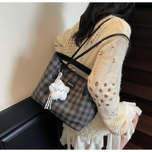 Detail of checkered tote bag featuring a star plush pendant and brand nameplate