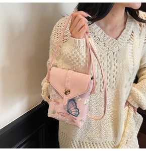 Détail de la broderie florale et du fermoir coeur doré sur un petit sac bandoulière rose