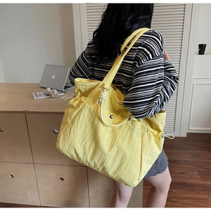 Détail du sac cabas jaune en nylon avec cordons de serrage latéraux et grande capacité