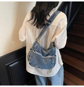 Detailed view of the multi-zipper denim bag with adjustable metal buckle on shoulder strap