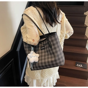 Detail of checkered tote bag with leather strap and white star plush pendant on stairs