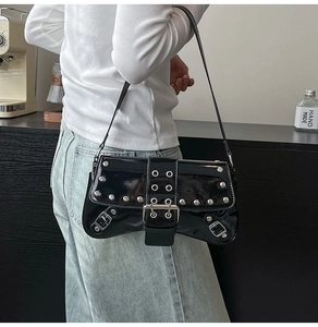 Detail of black patent leather underarm bag with silver rivets and punk style buckle