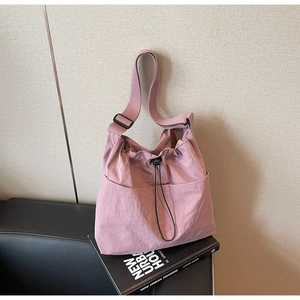 Detail of adjustable strap and drawstring closure on large pink nylon bucket bag