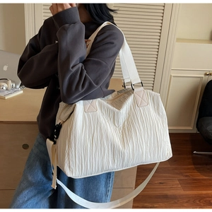 Detail view of large cream canvas tote bag with unique vertical pleated texture and strap