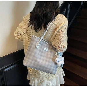 Detail of grey plaid tote bag with silver chain and plush star charm on a model