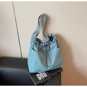 Detail view of light blue nylon bucket bag with drawstring closure and front pockets