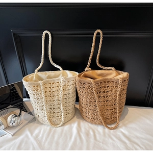Close-up of hollow woven straw bucket bags showing premium texture and shoulder straps