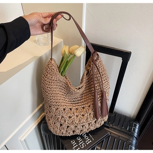 Détail du sac cabas en paille tissée avec glands en cuir marron et bandoulière