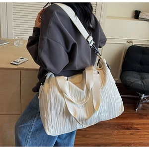 Detailed close-up of a white textured canvas tote bag with adjustable shoulder straps
