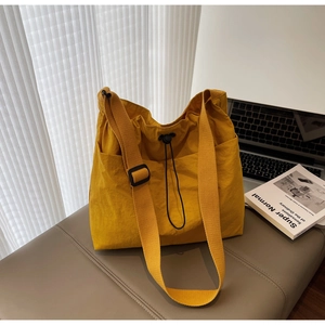 Detail of yellow waterproof nylon tote bag with drawstring closure and side pockets