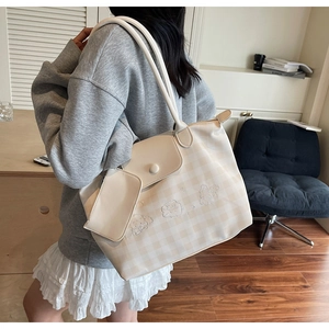 Close-up of beige checkered tote bag with cartoon embroidery and a matching mini pouch